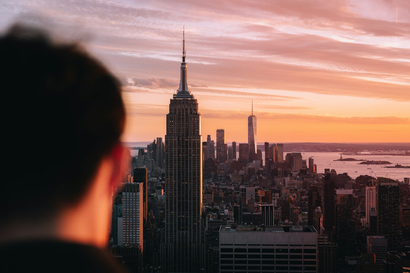 Person views new york city skyline at vibrant sunset.