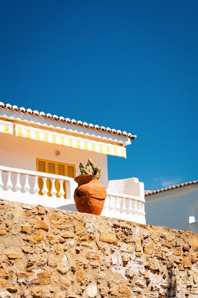 Mediterranean building with yellow awning and potted plant.